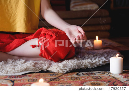 Close-up of woman's hand in yoga lotus pose meditating in a crafting room with candles 47920857