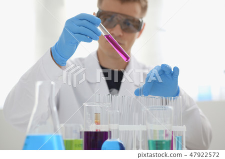 A male chemist holds test tube of glass 47922572