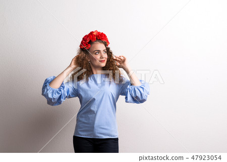 A front view of young beautiful woman with flower headband, hands behind head. 47923054