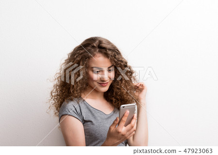 Young beautiful happy woman in studio, using smartphone. Young beautiful happy woman in studio, using smartphone. 47923063