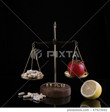 choice between drugs tablets, pills and natural fruits on the scales at black backdrop choice between drugs tablets, pills and natural fruits on the scales at black backdrop 47923692