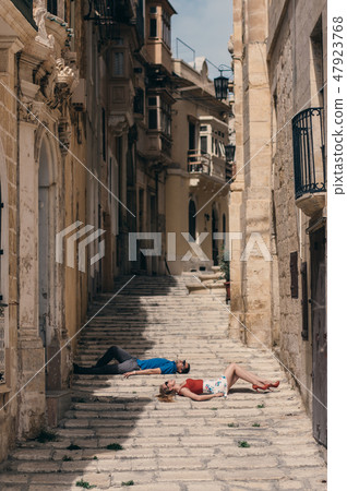 Man and woman laying on the stairs on the street Man and woman laying on the stairs on the street 47923768