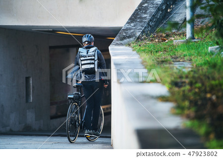 A rear view of male bicycle courier delivering packages in city. Copy space. 47923802