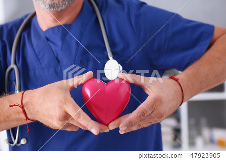 Male doctor hold in arms red heart Male doctor hold in arms red heart 47923905