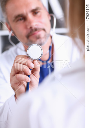 Handsome mature doctor hold in arm stethoscope head Handsome mature doctor hold in arm stethoscope head 47924195