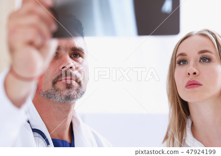 Mature male doctor hold in arm and look at xray photography Mature male doctor hold in arm and look at xray photography 47924199
