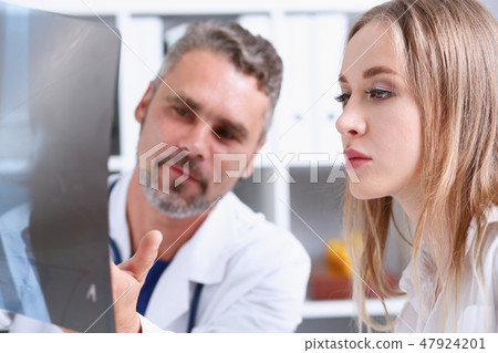 Mature male doctor hold in arm and look at xray photography Mature male doctor hold in arm and look at xray photography 47924201