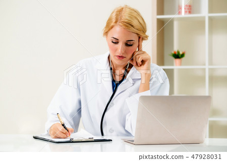 Young female doctor working in hospital office. 47928031