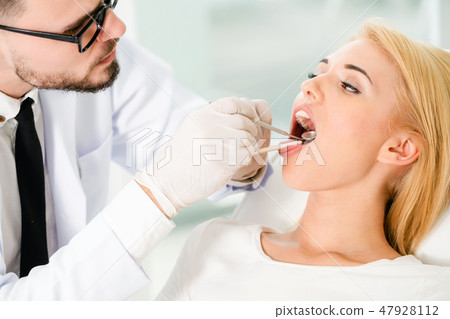 Young dentist examining patient in dental clinic. Young dentist examining patient in dental clinic. 47928112