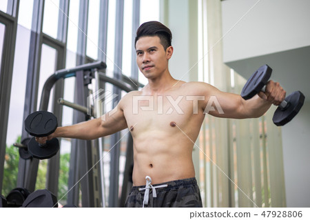 Muscular man bodybuilder training with dumbbells. 47928806