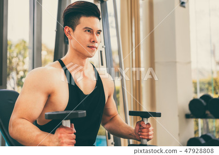 Muscular man bodybuilder training with dumbbells. 47928808