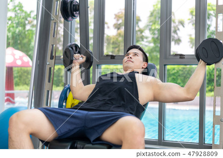 Muscular man bodybuilder training with dumbbells. 47928809