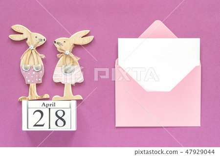 Calendar April 28, pair wooden easter bunnies, pink envelope with blank card on purple paper 47929044