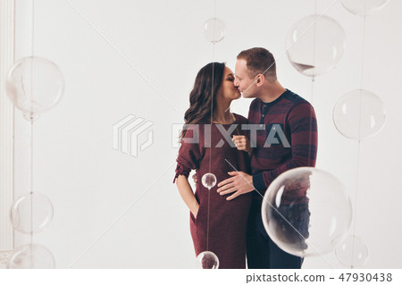 Family portrait: the husband embraces the pregnant wife on a white background. pregnant couple in Family portrait: the husband embraces the pregnant wife on a white background. pregnant couple in 47930438