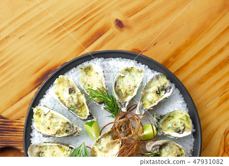 Oysters baked with cheese and herbs on plate on wooden background. Seafood background copy space Oysters baked with cheese and herbs on plate on wooden background. Seafood background copy space 47931082