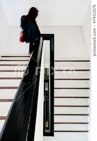 Woman walking on contemporary white stairwell Woman walking on contemporary white stairwell 47932876