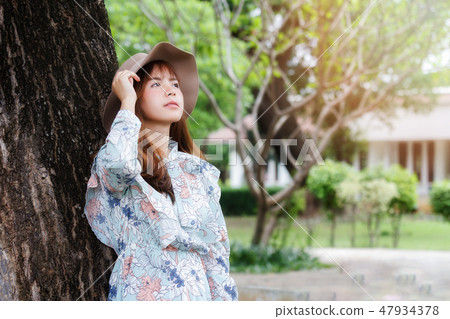 Pretty asian girl leaning against on the tree. 47934378
