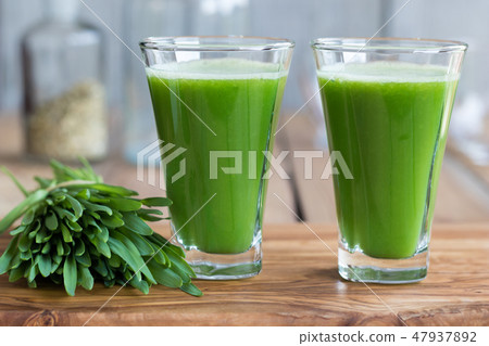 Two green barley grass shots on a wooden table 47937892