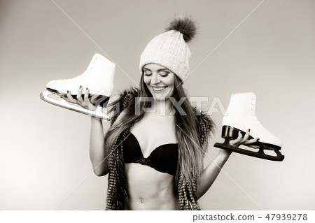Woman wearing bra and holding ice skates Woman wearing bra and holding ice skates 47939278