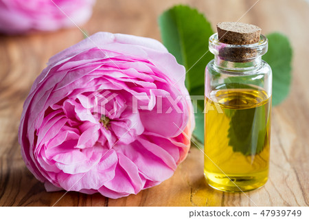 A bottle of essential oil with a rose flower A bottle of essential oil with a rose flower 47939749