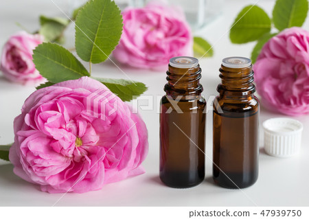 Two bottles of rose essential oil with roses Two bottles of rose essential oil with roses 47939750