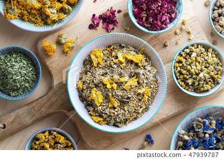 Dried herbs in bowls on a wooden table, top view 47939787