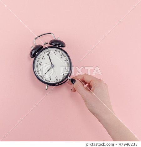 Female hand with alarm clock. Morning concept Female hand with alarm clock. Morning concept 47940235