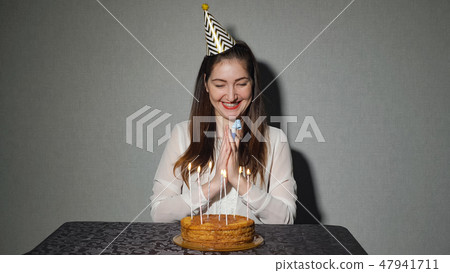 alone woman celebrates a holiday, he sits alone at a table with a cake and a candles alone woman celebrates a holiday, he sits alone at a table with a cake and a candles 47941711