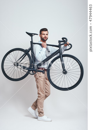 Take a bike! Full length of good looking man in casual clothes carrying his bicycle. Urban style Take a bike! Full length of good looking man in casual clothes carrying his bicycle. Urban style 47944463