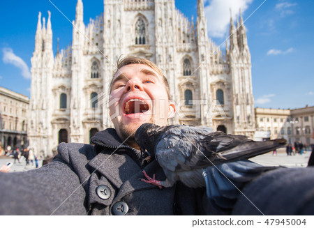Travel, holidays and winter vacations concept - Happy man take selfie photo with funny pigeons in 47945004
