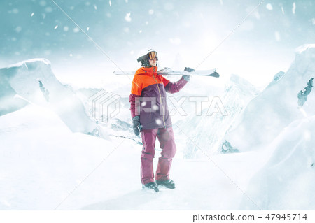 Female skier standing with skies in one hand on background mountain landscape 47945714