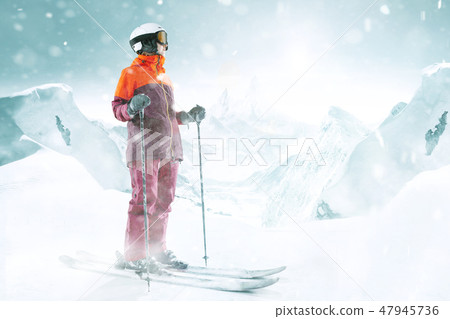 Female skier standing with skies in one hand on background mountain landscape 47945736