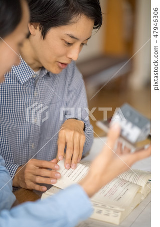 A designer of a leading general contractor who teaches the procedure of application for building confirmation while utilizing a model of a house 47946306