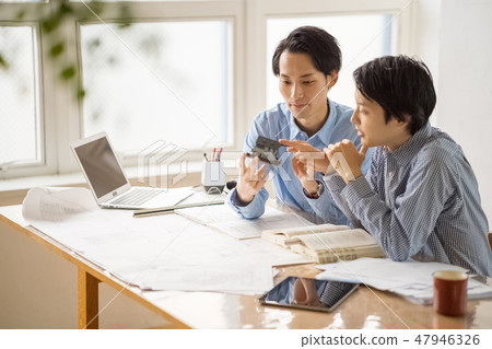 A young male employee who learns from the trustworthy seniors the studies of first class architects and studies pleasantly happily 47946326