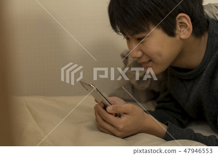 A boy who uses smartphone in bed sleep sleepy junior high school student high school student 47946553