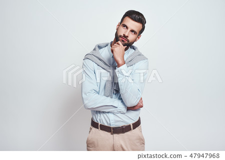 Maybe is...Charming young man with hand on chin thinking about question with thoughtful face while Maybe is...Charming young man with hand on chin thinking about question with thoughtful face while 47947968