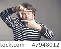 Young handsome shaggy curly man focusing with fingers, framing with hands on grey background, copy 47948012