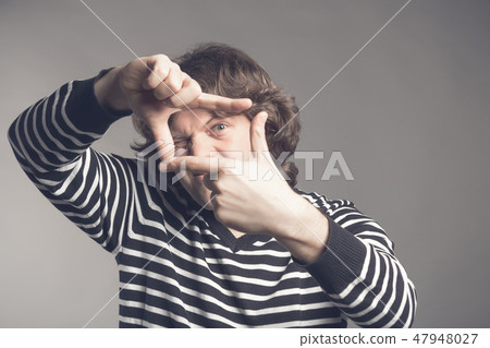 Young handsome man focusing with fingers, framing with hands isolated on grey background. Close up Young handsome man focusing with fingers, framing with hands isolated on grey background. Close up 47948027