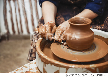 Ceramics. The master on the potter's wheel produces a vessel of clay, undercutting the form. Ceramics. The master on the potter's wheel produces a vessel of clay, undercutting the form. 47949812