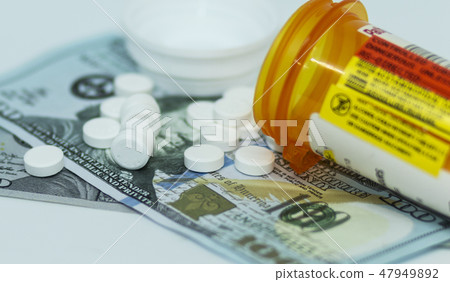 Oxycodone pills spilling onto hundred dollar bills Oxycodone pills spilling onto hundred dollar bills 47949892