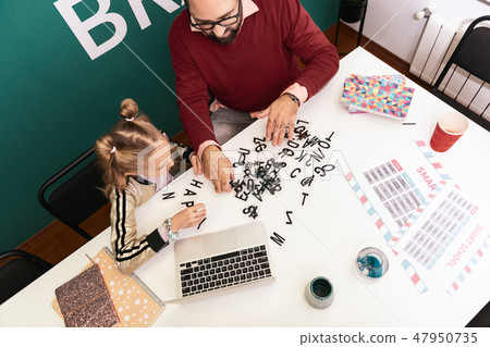 Dark-haired bearded adult teacher in eyewear having a lesson with his pupil Dark-haired bearded adult teacher in eyewear having a lesson with his pupil 47950735