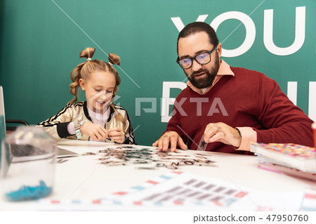 Cute fair-haired girl with bracelets on her hand making words from letters 47950760