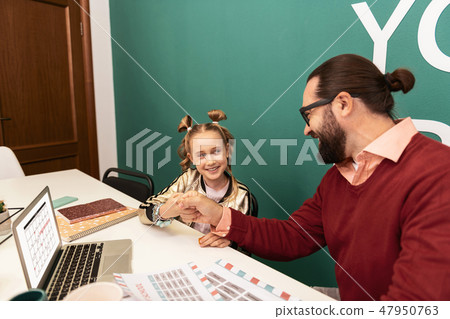 Cute fair-haired girl with bracelets on her hand spending her time at school 47950763