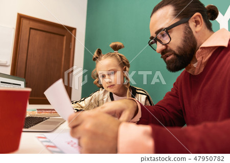 Cute fair-haired girl with bracelets on her hand looking concentrated Cute fair-haired girl with bracelets on her hand looking concentrated 47950782