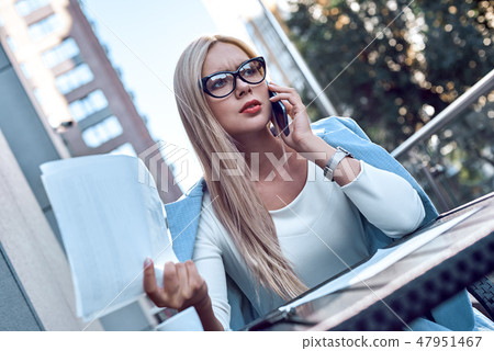 Fashionable businesswoman sitting in a cafe discussing the terms of the contract by phone Fashionable businesswoman sitting in a cafe discussing the terms of the contract by phone 47951467