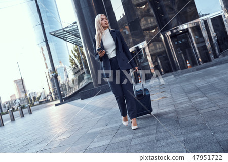 Full length portrait of a smiling successful businesswoman pulling suitcase Full length portrait of a smiling successful businesswoman pulling suitcase 47951722