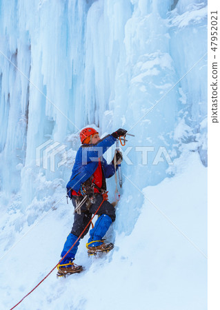 rock climber screwing ice screw into glacier 47952021