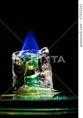 Blue flame melting down green icecube in the dark 47952242