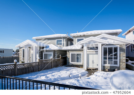 Residential duplex house with front yard in snow on bright winter day in Canada Residential duplex house with front yard in snow on bright winter day in Canada 47952604
