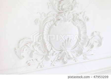 Beautiful ornate white decorative plaster mouldings in studio. The white wall is decorated with Beautiful ornate white decorative plaster mouldings in studio. The white wall is decorated with 47953209